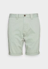 Shorts vert clair en coton. Dotés de revers roulés, d'une fermeture à bouton à l'avant et de passants de ceinture. Texture lisse sans motifs visibles.