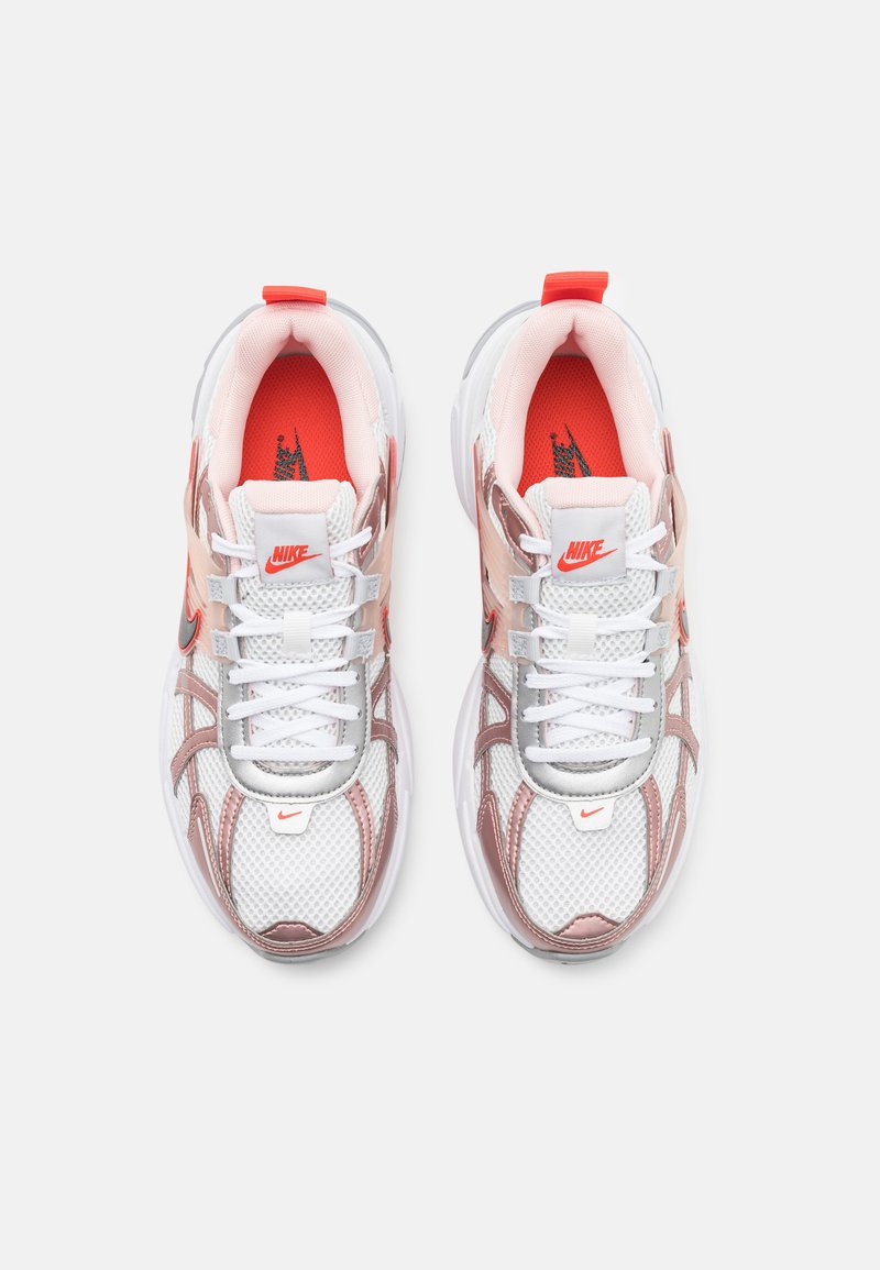 Le scarpe Nike presentano una tomaia in rete bianca con accenti rosa e rossi, un collare imbottito e una robusta suola bianca. Logo prominente sulla linguetta.