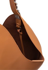 Sac fourre-tout en cuir beige avec une texture lisse, doté d'un dessus ouvert, d'une poche intérieure et d'un attachement de bandoulière en chaîne argentée épaisse.