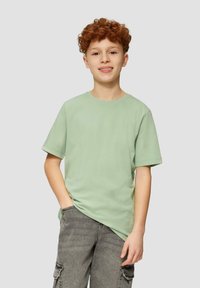 Lichtgroen katoenen T-shirt met korte mouwen, ronde halslijn en een relaxte pasvorm, gedragen met grijze cargoshorts met zijzakken.