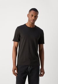 Sort bomulds-T-shirt med rund halsudskæring og korte ærmer, prydet med et subtilt logo-detail på brystet. Bæres med mørk denim jeans.