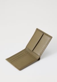 Olive green leather wallet with textured finish, featuring multiple card slots and a flap closure. "HUGO" logo embossed on the side.