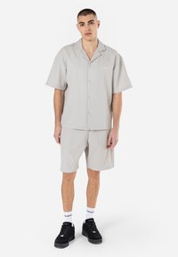 Grey short-sleeve shirt and matching shorts set. Made from textured fabric with a ribbed design, featuring a casual collar and button closure.