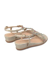 Sandales compensées beige avec une texture en daim lisse, ornées d'accents de bijoux décoratifs le long des brides et d'une boucle ajustable à la cheville.