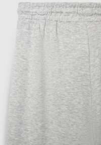 Hellgraue Jogginghosen mit einem elastischen, gerafften Bund und weichem, strukturiertem Stoff. Seitliche Taschen an den Außennähten sichtbar.