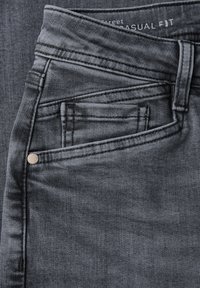 Jeans en denim gris avec une coupe décontractée, présentant une petite poche avant, des coutures visibles et un détail de bouton en métal à la taille.