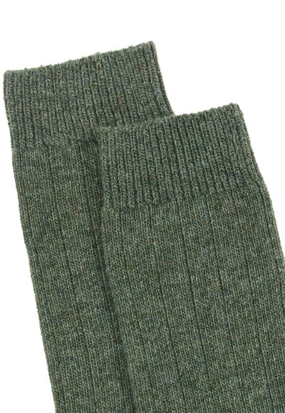 Grüne gerippte Socken mit einer strukturierten Strickart. Das Material wirkt warm und langlebig und weist eine gleichmäßige Farbe auf.