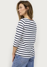 Marineblauwe en witte gestreepte t-shirt met driekwartmouwen. Gemaakt van zachte stof, het heeft een ronde hals en een ontspannen pasvorm.