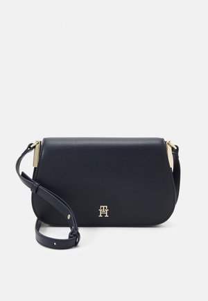 Sac bandoulière en cuir noir avec sangle réglable, quincaillerie dorée et petit logo doré au centre avant.