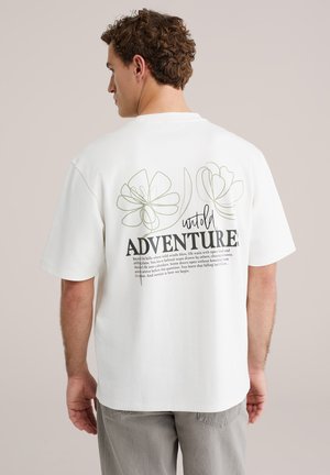 T-shirt en coton blanc à coupe décontractée, avec des fleurs dessinées en lignes vertes et un texte noir indiquant « untold ADVENTURE » au dos.