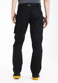 Un pantalon de travail noir comporte plusieurs poches, un tissu durable et des coutures renforcées. La taille a des accents jaunes et une passante de ceinture.