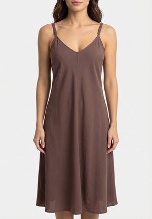 Femme portant une robe midi marron sans manches avec un décolleté en V et des bretelles spaghetti réglables, debout sur un fond blanc uni.