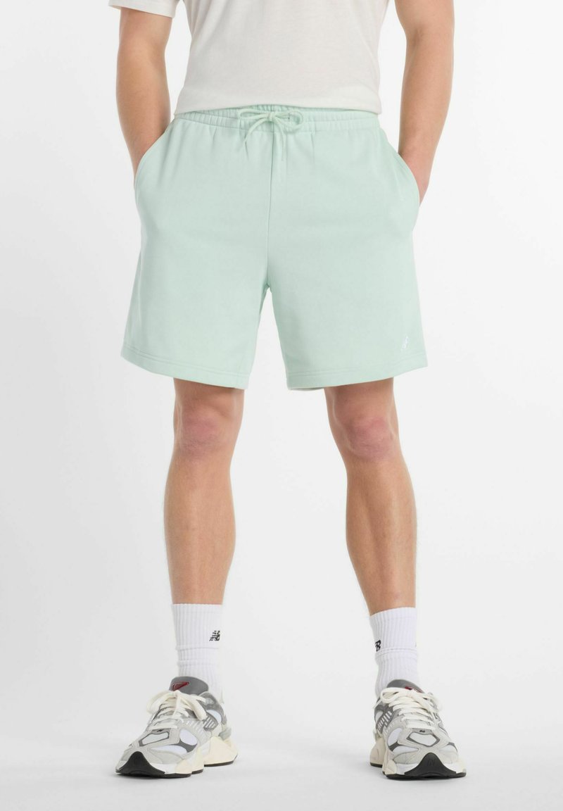 Pantalones cortos de un suave color verde menta, confeccionados en un material blando, con una cinturilla elástica y cordón de ajuste, además de bolsillos laterales. Corte clásico y diseño limpio.