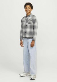 Grå rutigt skjorta med två bröstfickor, knappstängning, kombinerad med lösa ljusblå jeans och silverfärgade sneakers. Enkel, avslappnad outfit.