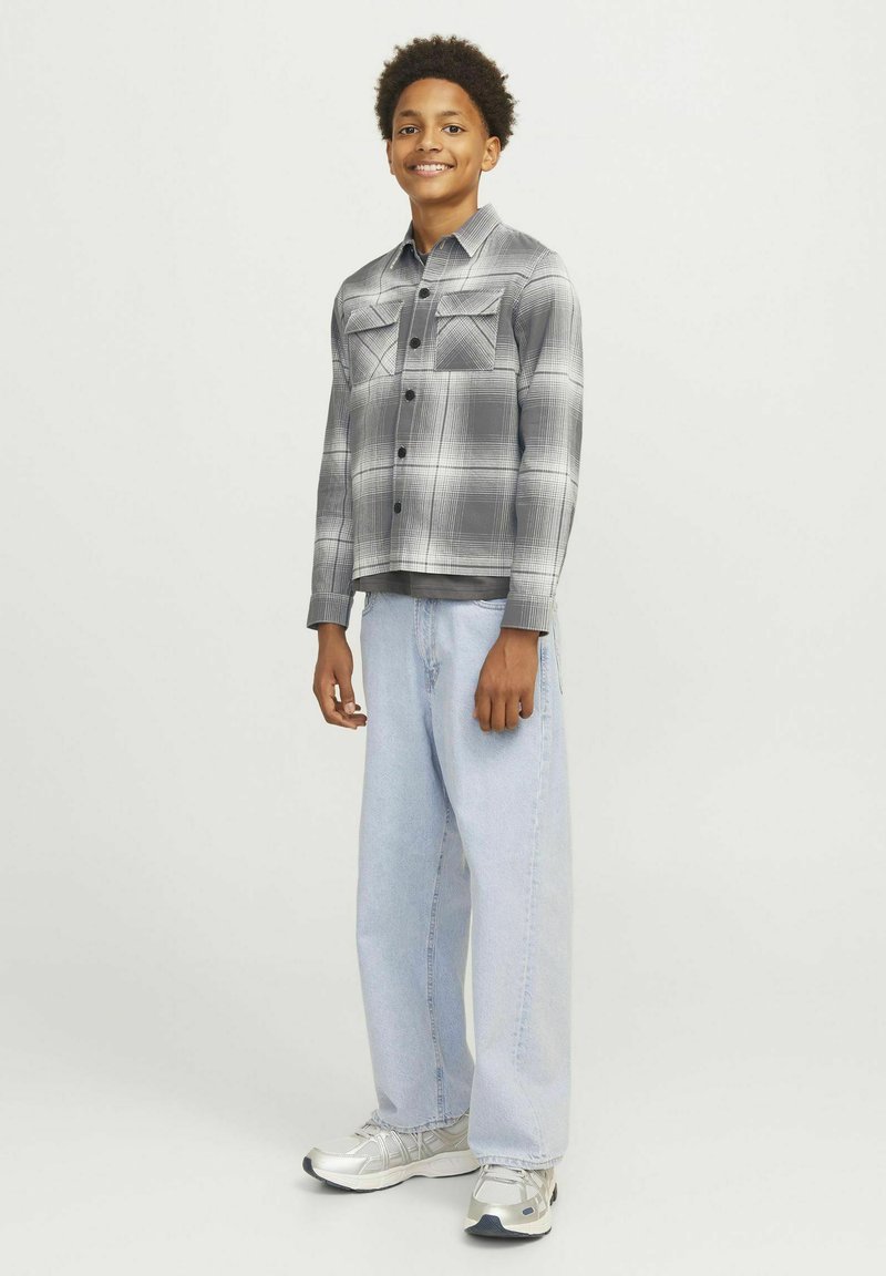 Grå rutigt skjorta med två bröstfickor, knappstängning, kombinerad med lösa ljusblå jeans och silverfärgade sneakers. Enkel, avslappnad outfit.
