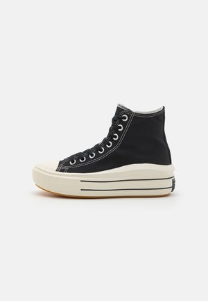 Zapatilla alta de lona negra con costuras blancas, punta de goma y suela texturada con rayas negras a lo largo de la entresuela.