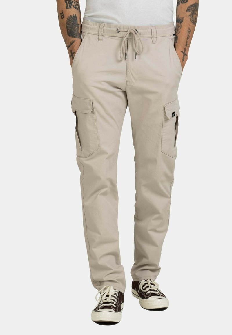 Beige Cargo-Hosen mit elastischem Bund und verstellbarem Kordelzug, featuring mehrere Seitentaschen und einer entspannten Passform.