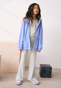 Light blue zip-up hoodie, gray top, gray flared pants, white sneakers with light blue accents; smooth fabric, relaxed fit, layered look.