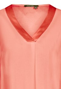 Koralfarvet bluse med V-hals og satinfinish. Stof er glat og let, med en subtil glans og uden synlige mønstre.