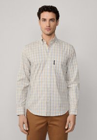 Camisa de cuadros en crema, azul y naranja, con manga larga y un bolsillo en el pecho. Fabricada en una tela de algodón ligera.