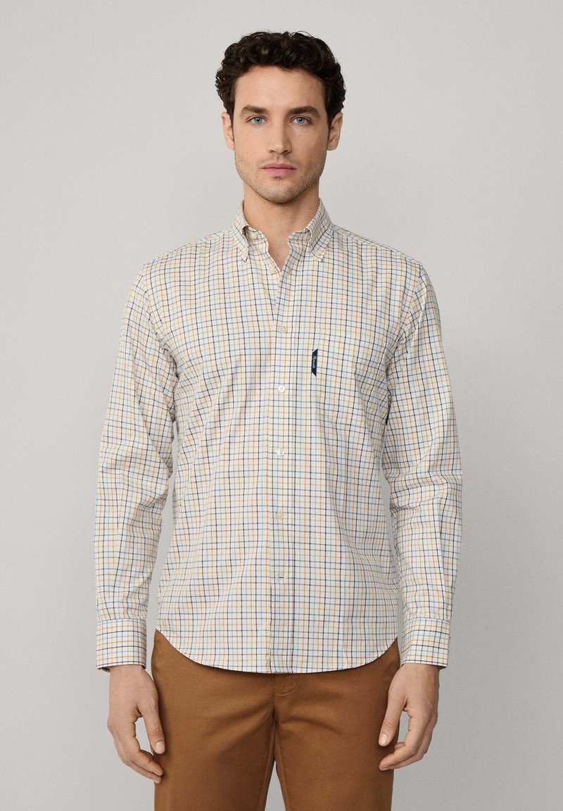 Camisa de cuadros en crema, azul y naranja, con manga larga y un bolsillo en el pecho. Fabricada en una tela de algodón ligera.