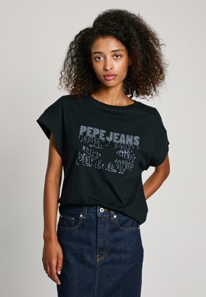 T-shirt noir à manches courtes avec un col rond ornée de lettres en strass. Associée à une jupe en denim bleu. Design simple et décontracté.