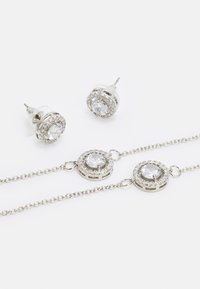 Silbernes Schmuckset mit runden Ohrringen und passendem Armband, verziert mit klaren Edelsteinen und glitzernden Akzenten.
