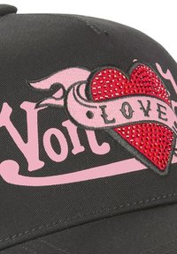 Gorra negra con texto "No" en rosa y parche de corazón de strass rojo que incluye una pancarta rosa con la palabra "AMOR" sobre el corazón.