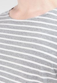 Camiseta de rayas gris y blanca con escote redondo, fabricada en algodón suave y con rayas horizontales de igual anchura.