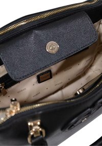 Borsa a tracolla in pelle nera con esterno texturizzato, hardware dorato e un ampio interno beige con etichetta del marchio e tasca con zip.