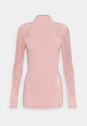 Top moulant rose à manches longues avec des détails en dentelle sur les manches et les côtés, avec un col haut et des panneaux avant et arrière unis.