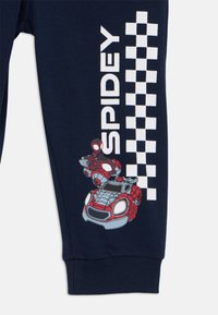 Pantalons de survêtement bleu marine avec un grand texte "SPIDEY" et un graphique coloré d'un personnage Spider-Man rouge dans un véhicule à thème.