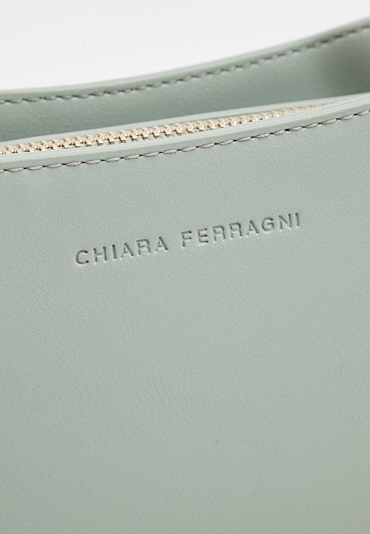 Hellgrüne Lederhandtasche mit glatter Oberfläche, goldener Reißverschluss und geprägtem Markennamen "CHIARA FERRAGNI" an der Seite.