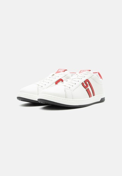 Λευκά αθλητικά παπούτσια χαμηλού ύψους με κόκκινο λογότυπο "S" στο πλάι, κόκκινες λεπτομέρειες στη γλώσσα και τη φτέρνα, και μαύρες λαστιχένιες σόλες.