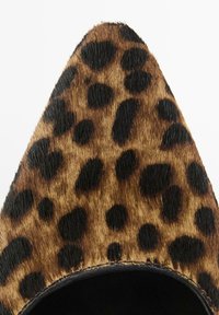 Bout pointu de chaussure à imprimé léopard avec une texture en fourrure marron et noire et doublure intérieure noire.