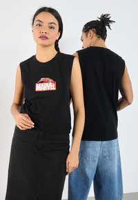 Must värvitu särk, mille esiosas on punane ja sinine Marveli graafika. Kandmiseks koos mustade denimseeliku ja helesiniste denimshortsidega.