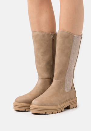 Knee-high beige boots with a smooth synthetic upper, elastic side panel, and chunky rubber sole. Features a side zipper for easy wear.