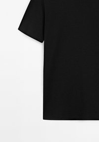 Maglietta nera in cotone a maniche corte disposta piatta, mostrata di fianco con la manica sinistra contro uno sfondo bianco.