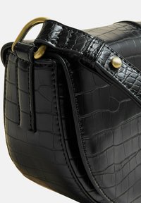 Borsa in pelle nera con un motivo testurizzato a coccodrillo, forma curva, hardware dorato e una tracolla rimovibile con bottoni a pressione.