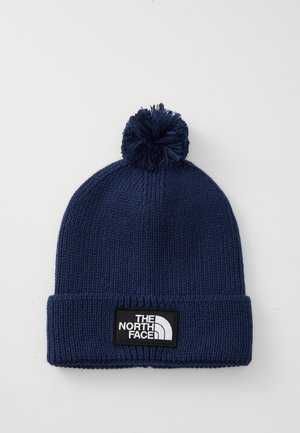 Navy blue knitted beanie with pom-pom and folded cuff featuring "The North Face" black and white logo patch.
