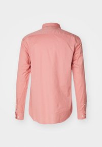 Camicia a maniche lunghe di cotone color rosa chiaro. Presenta un colletto e polsini con bottoni, una texture liscia e un dettaglio nella parte posteriore.