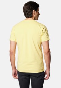 Żółta bawełniana koszulka z krótkim rękawem, z żebrowanym okrągłym dekoltem i gładką powierzchnią. Brak widocznych logo lub wzorów z tyłu.