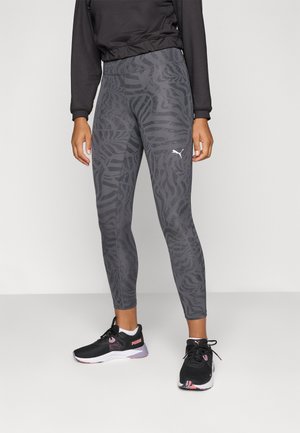 Sorte leggings med et gråt dyreprint mønster, lavet af strækbart stof, parret med sorte sportssko med lyserøde accenter og hvide såler.
