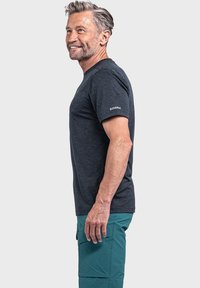 Kohlegraues T-Shirt mit kurzen Ärmeln und Rundhalsausschnitt, aus einem weichen Material, mit einem Logo auf dem linken Ärmel. Kombiniert mit tealfarbenen Cargo-Shorts.