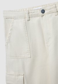 Beżowe spodnie cargo z elastycznym paskiem w talii, przednimi i bocznymi kieszeniami oraz pojedynczym zapięciem na guzik. Wykonane z trwałej bawełny.