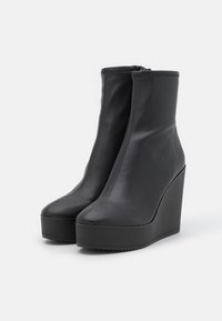 Melnas ādas iešļūcamas potīšu kurpes ar gludu virsmu, rāvējslēdzēju un noapaļotu pirkstu dizainu. Iespējo bieza platforma un augsta kāju papēža.