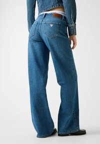 Τζιν με φαρδύ παντελόνι από τζιν υλικό σε μεσαίο μπλε χρώμα. Διαθέτει πίσω λογότυπο, δύο πίσω τσέπες και διακριτικές ραφές.