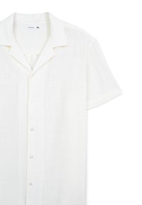 Camicia bianca a maniche corte realizzata in tessuto leggero. Presenta un colletto a laccetto, sei bottoni sul davanti e una finitura testurizzata.