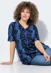 Námořnická modrá halenka s krátkým rukávem a výstřihem do V, s hravým modrým textovým vzorem. Lehce materiál s volným, uvolněným střihem.