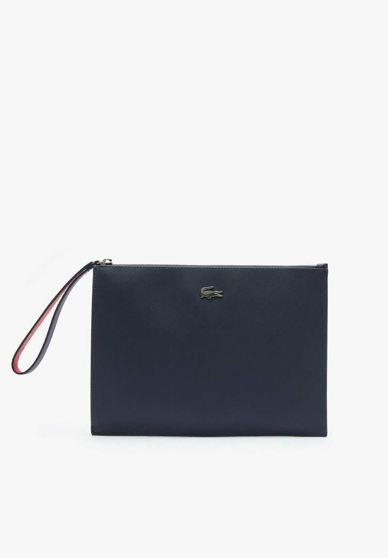 Pochette bracelet texturée bleu marine avec logo crocodile argenté et bracelet assorti avec dessous rouge, forme rectangulaire et fermeture zippée.